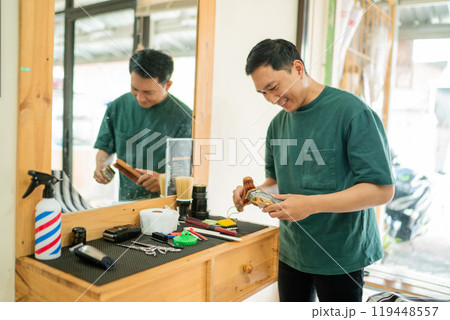 A man is currently standing in front of a mirror in a barber shop setting A man is currently standing in front of a mirror in a barber shop setting 119448557
