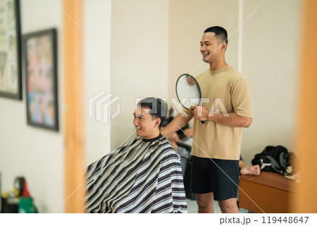 A man is currently getting his hair cut by a barber in a room 119448647