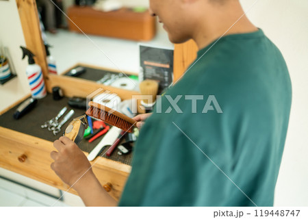 A man brushes his hair in front of a mirror at a barbershop 119448747