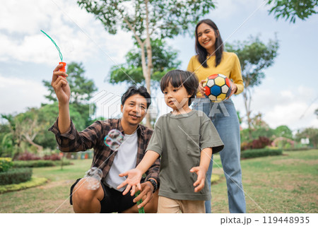 father makes bubbles and his son catches when the family plays together father makes bubbles and his son catches when the family plays together 119448935