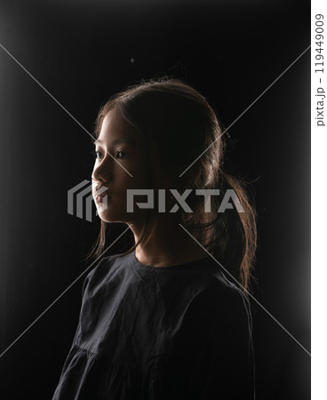 A Thoughtful Child Portrait Captured in Dramatic and Evocative Lighting 119449009