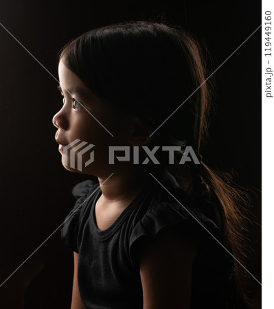 Profile Portrait of a Young Girl in Soft Light Against a Dark Background 119449160