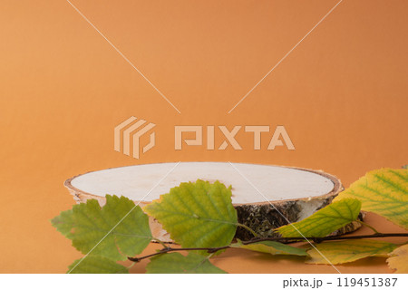 Podium made of natural birch lumber with leaves on an orange background. 119451387