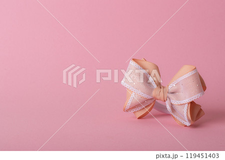 A beautiful bow made of turnip ribbon on a light pink background. copy space. A beautiful bow made of turnip ribbon on a light pink background. copy space. 119451403
