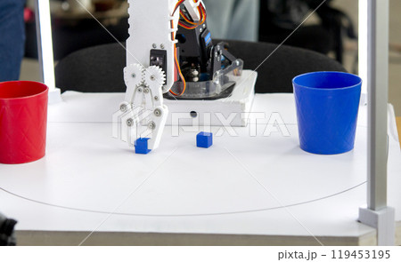 Robot automatic hand taking cubes and putting in glass. Automatic robotic arm distinguishing color of cube and putting in glass of same color. Automation, modern technologies. Artificial Intelligent 119453195