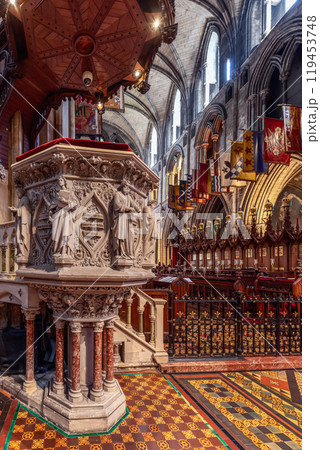 The intricately carved stone pulpit in St. Patrick Cathedral, Dublin, stands on marble columns with gothic figures. The surrounding mosaic floor and arches highlight the cathedral historic and sacred The intricately carved stone pulpit in St. Patrick Cathedral, Dublin, stands on marble columns with gothic figures. The surrounding mosaic floor and arches highlight the cathedral historic and sacred 119453748