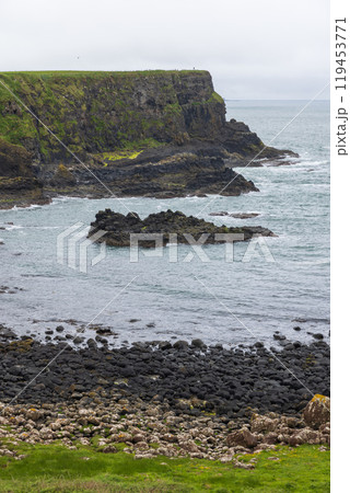 Bay of the Cow with rocky shore and towering basalt cliffs layered with earth formations Bay of the Cow with rocky shore and towering basalt cliffs layered with earth formations 119453771