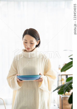 食器を持ち歩く女性 119454035
