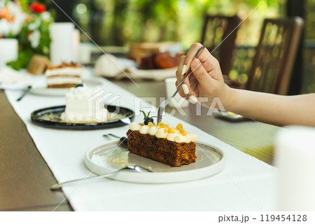 Woman hand with fork eating carot cake in cafe. Woman hand with fork eating carot cake in cafe. 119454128