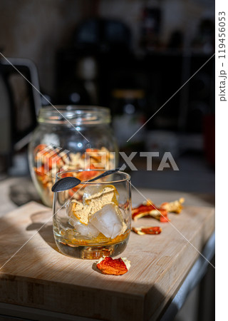 Preparation of fly agaric drink, ground powdered dry mushroom on ice cubes in a glass, illuminated by natural sunlight.  Homemade fly agaric elixir.   119456053
