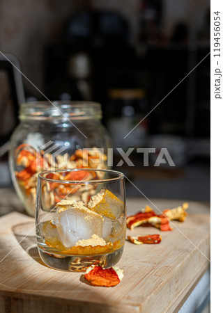 Preparation of fly agaric drink, ground powdered dry mushroom on ice cubes in a glass, illuminated by natural sunlight. Homemade fly agaric elixir. Preparation of fly agaric drink, ground powdered dry mushroom on ice cubes in a glass, illuminated by natural sunlight. Homemade fly agaric elixir. 119456054