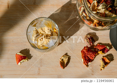 Preparation of fly agaric drink, ground powdered dry mushroom on ice cubes in a glass, illuminated by natural sunlight.  Homemade fly agaric elixir. Top View 119456061