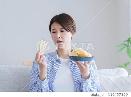 ポテトチップスを食べるか悩む女性（ポテチ・ダイエット・太る・不健康） 119457199