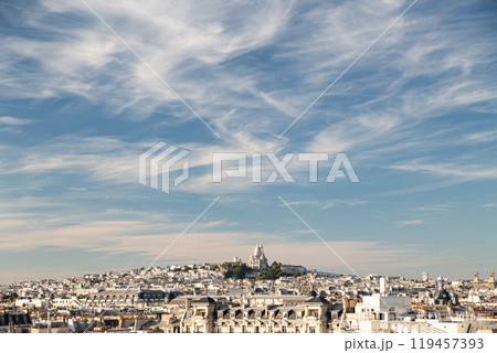 Beautiful view of Montmartre hill and Sacre Coeur Basilica against a blue sky with clouds Beautiful view of Montmartre hill and Sacre Coeur Basilica against a blue sky with clouds 119457393