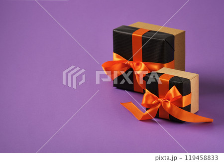 Banner with black gift boxes with orange ribbon on purple background. Space for your text. Selective Focus. 119458833