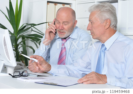 Two old business men sitting at desk and working 119459468