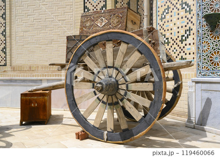 Old wooden cart with wooden chests next to brick house with Uzbek ornaments in Samarkand, Uzbekistan Old wooden cart with wooden chests next to brick house with Uzbek ornaments in Samarkand, Uzbekistan 119460066