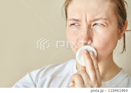 Woman contemplating skincare routine with cotton pad in natural light indoor Woman contemplating skincare routine with cotton pad in natural light indoor 119461964