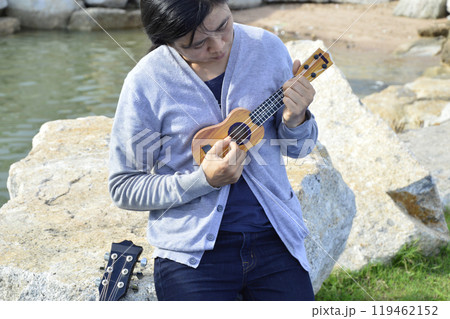 Front view of Asian woman playing ukulele Front view of Asian woman playing ukulele 119462152