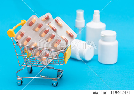 Pills and Capsules in Shopping Cart on Blue Background 119462471