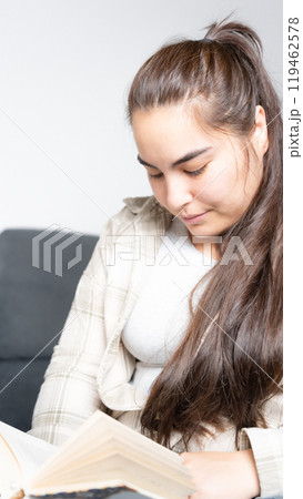 Young relaxed woman reading book while sitting on the sofa. High quality photo 119462578