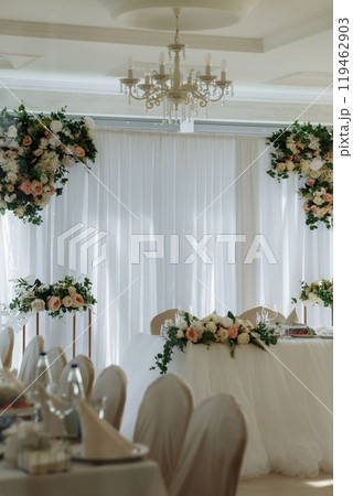 A wedding reception with a white backdrop and floral decorations 119462903