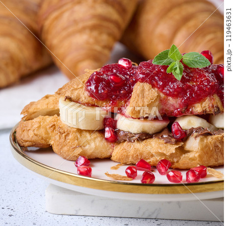 Croissant with chocolate, banana pieces and raspberry jam on a plate Croissant with chocolate, banana pieces and raspberry jam on a plate 119463631