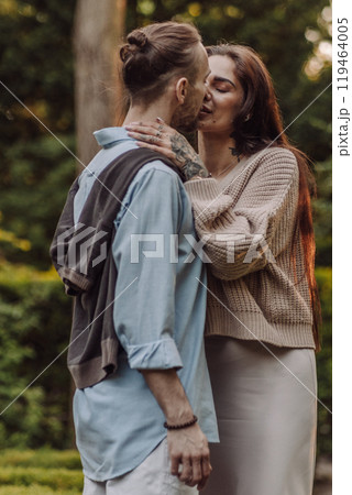 Love, hug and happy with couple in park for romance, bonding and summer vacation. Loving young couple hugging and smiling together on nature background. Beautiful girl with tattooed body outdoor. Love, hug and happy with couple in park for romance, bonding and summer vacation. Loving young couple hugging and smiling together on nature background. Beautiful girl with tattooed body outdoor. 119464005