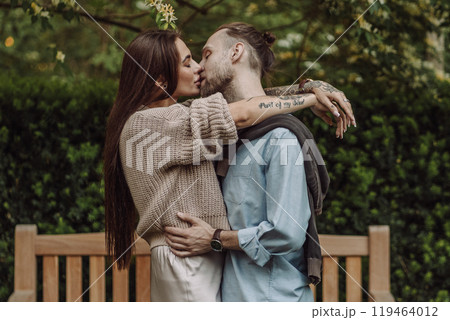Happy loving couple enjoying their time together in park. Loving couple spending time together. Girl with tattoos. Tattooed woman. Beautiful fashionable couple of lovers on the street. 119464012