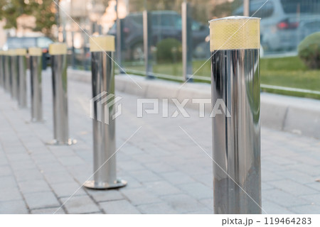 Urban Modernity: A Row of Gleaming Reflective Bollards in a City Setting Urban Modernity: A Row of Gleaming Reflective Bollards in a City Setting 119464283
