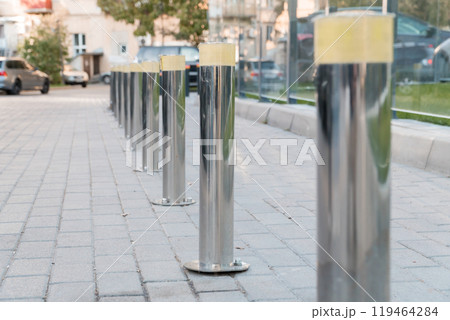 Polished Silver Bollards Line a Paved Pathway in Urban Setting Polished Silver Bollards Line a Paved Pathway in Urban Setting 119464284