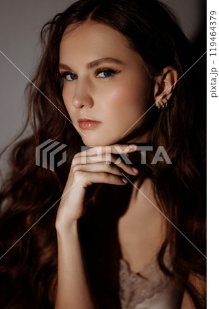 A woman with long brown hair and blue eyes is posing for a photo A woman with long brown hair and blue eyes is posing for a photo 119464379