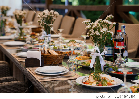 Elegant Outdoor Banquet Table Set for a Festive Gathering with Floral Decor and Assorted Dishes 119464394