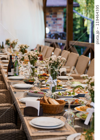 Elegant Outdoor Banquet Setup with Floral Decor and Gourmet Dishes in a Rustic Setting 119464395