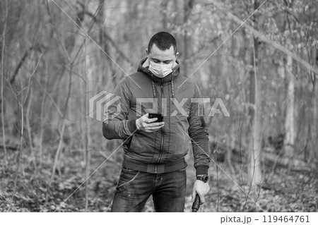 Man in Mask Texting in a Forest Setting Man in Mask Texting in a Forest Setting 119464761