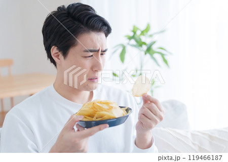 ポテトチップスを食べるか悩む男性（ポテチ・ダイエット・太る・不健康） 119466187