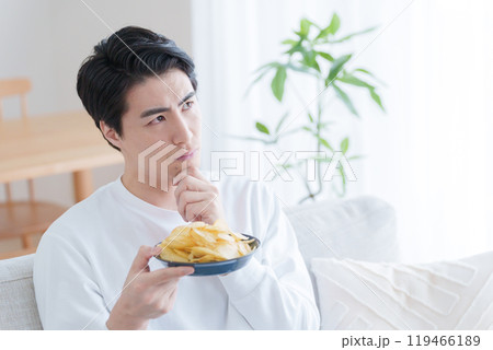 ポテトチップスを食べるか悩む男性(ポテチ・ダイエット・太る・不健康) ポテトチップスを食べるか悩む男性(ポテチ・ダイエット・太る・不健康) 119466189