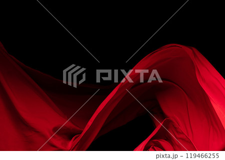 Red Cotton fabric flying in curve shape, Piece of textile Red cotton fabric throw fall in air. Black background isolated, dark shading environment 119466255
