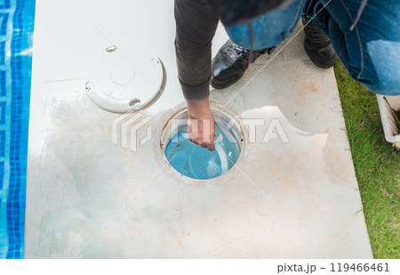 Person cleaning pool filter skimmer basket. Cleaning and maintenance of the swimming pool skimmer basket 119466461
