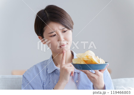 ポテトチップスを食べるか悩む女性（ポテチ・ダイエット・太る・不健康） 119466803