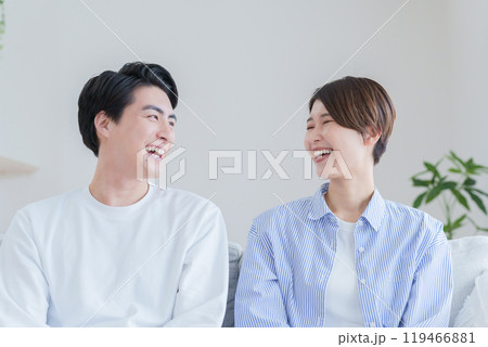 家のリビングで過ごす笑顔の30代夫婦 119466881