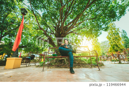 Photographer sitting on a bench checking his camera. Male photographer checking dslr camera sitting on a bench 119466944