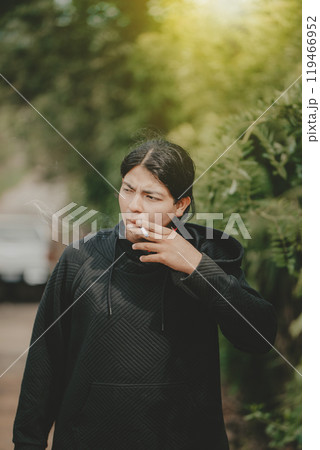 Young man smoking cigarette on the street. Portrait of handsome guy smoking outdoors 119466952