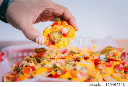 Close up of hand of taking nachos on isolated background. Hand taking and showing a nacho isolated Close up of hand of taking nachos on isolated background. Hand taking and showing a nacho isolated 119467348