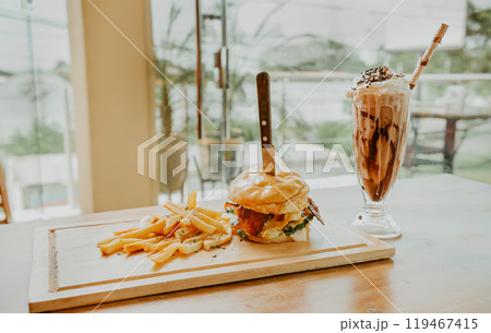 Hamburger with fries and milkshake served on wooden board with space for text 119467415
