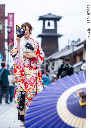 時の鐘の前でポーズをとる振袖の若い女性 119467468