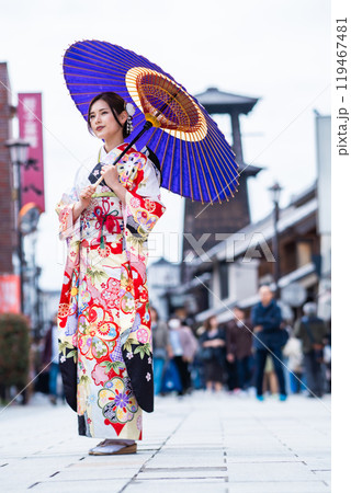 時の鐘の前でポーズをとる振袖の若い女性 119467481