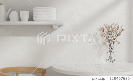 A round white dining table with a vase, a wooden armchair, and a wall shelf displaying kitchenware. 119467680