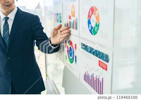 マーケティングデータのグラフを見せて説明する男性ビジネスパーソン マーケティングデータのグラフを見せて説明する男性ビジネスパーソン 119468100