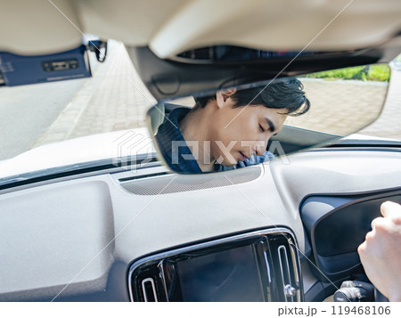 居眠り運転する男性ドライバーのルームミラー越しの表情 119468106
